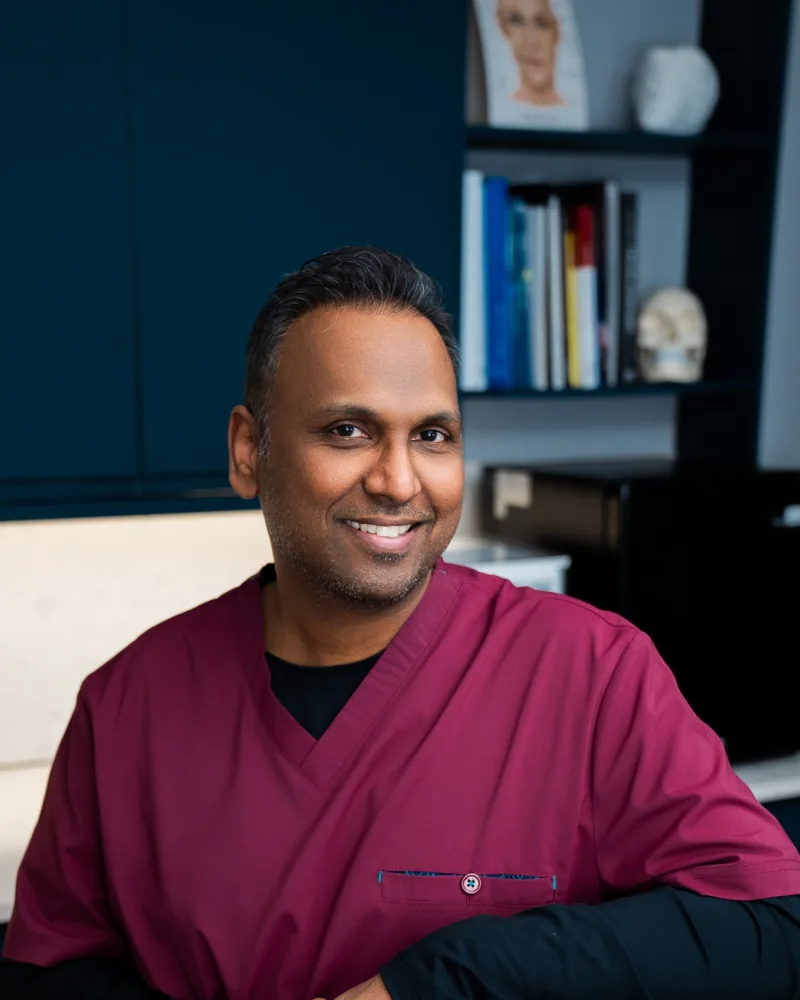 Dr Nick smiling beside the treatment chair in a consultation room at Rejuvena Clinic, Bedford
