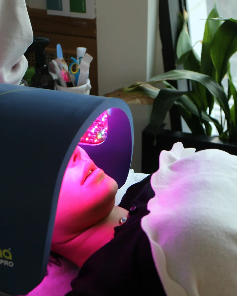 A patient receiving Dermalux&reg; LED light therapy under the glowing LED panel at Rejuvena Clinic, Bedford