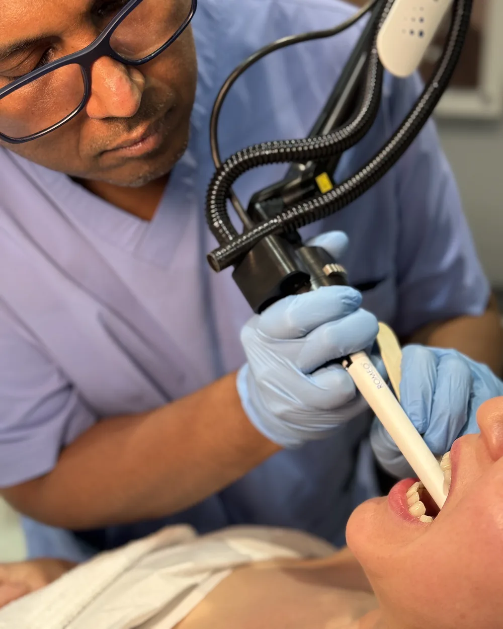 Dr Nick guiding the Romeo&trade; Er:YAG laser handpiece into a patient’s mouth during anti-snoring treatment at Rejuvena Clinic, Bedford