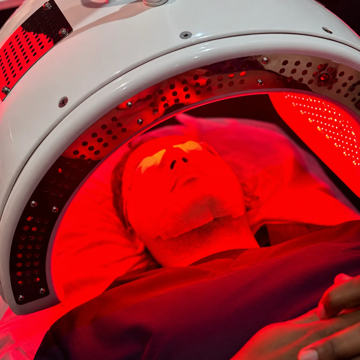 Close-up of a client lying under the red light of the Dermalux® Triwave LED canopy at Rejuvena Clinic, Bedford